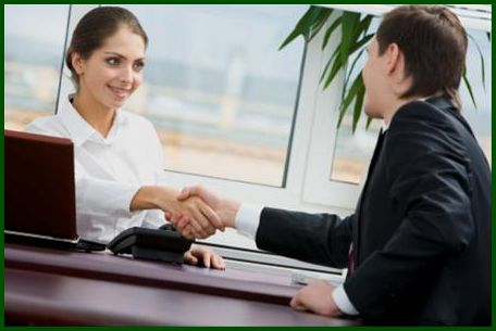 Sales rep and customer shaking hands across a desk.